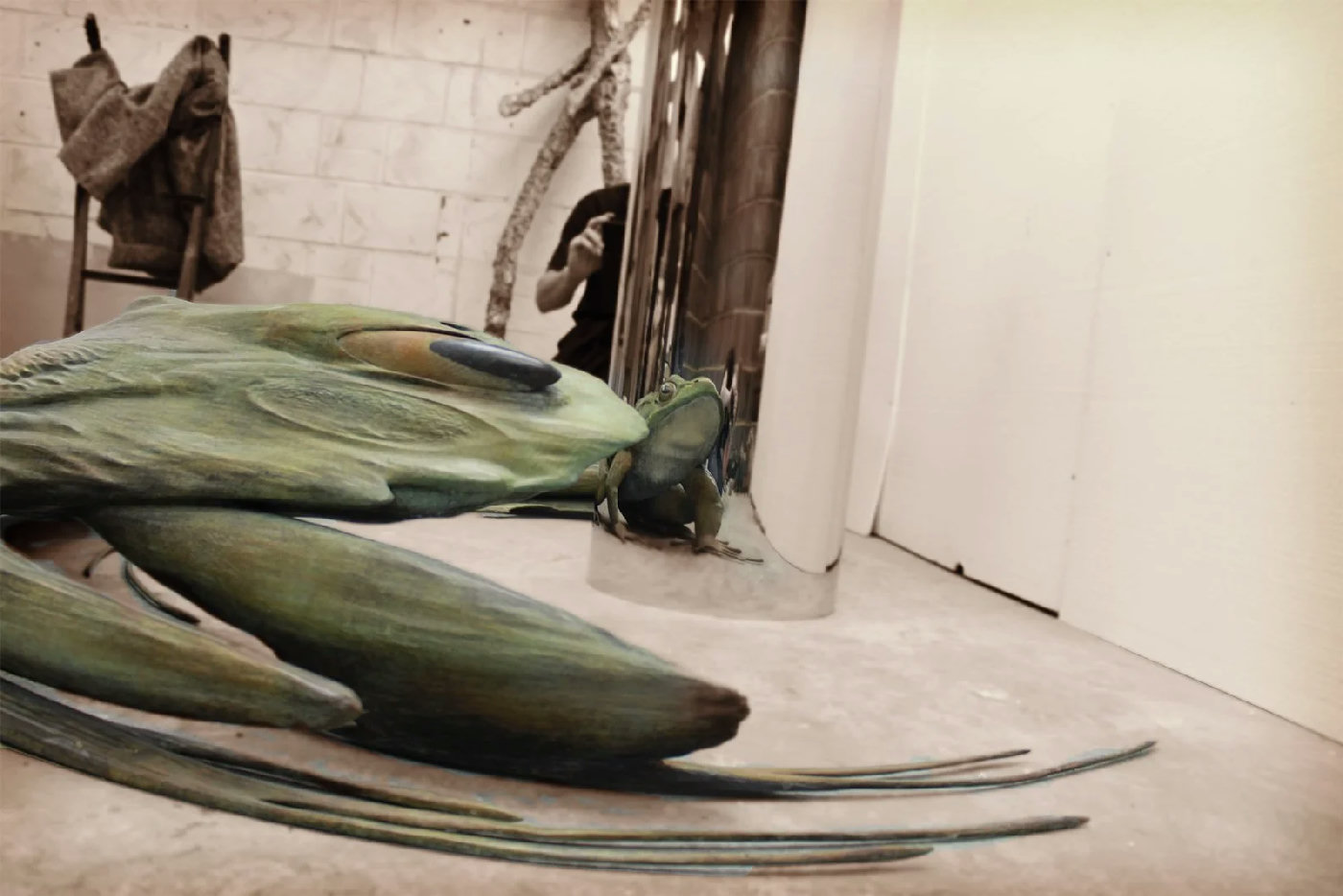 Extinction? by Jonty Hurwitz: large green anamorphic frog sculpture beside a tall steel cylindrical mirror